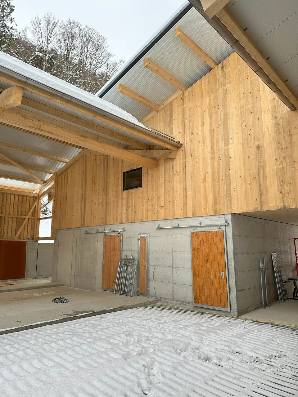Aussenansicht des Laufstalls in Riedtwil mit Holzfassade und Vordach
